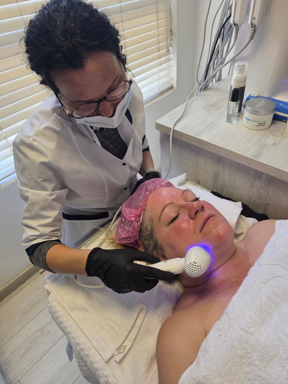 A therapist performing a facial treatment with a handheld device